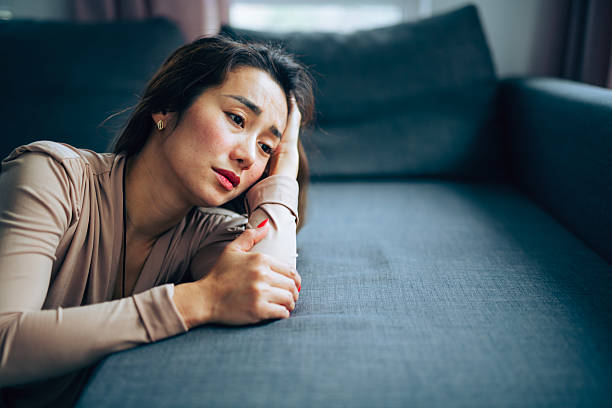 Woman kneeling next to a green couch looking sad and stressed