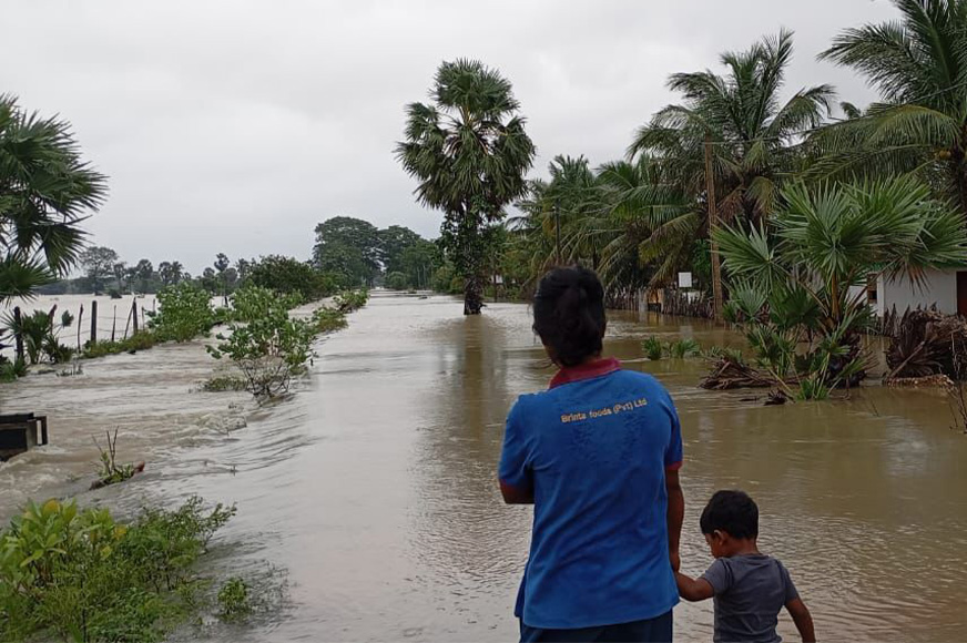 A son clings to his father’s hand as they wade through flooded waters after a cyclone.