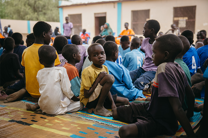 A group of children sit together at a local safety center for a time of education, play and support.