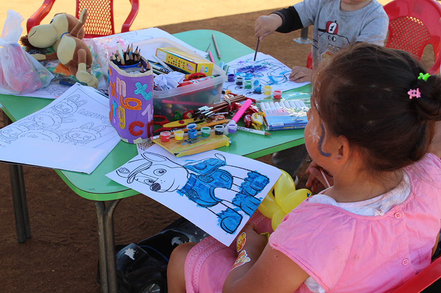 A girl sits at an arts and crafts table.