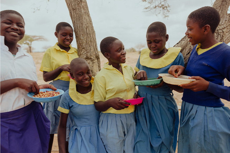A group of girls in school uniforms share a meal together at school.