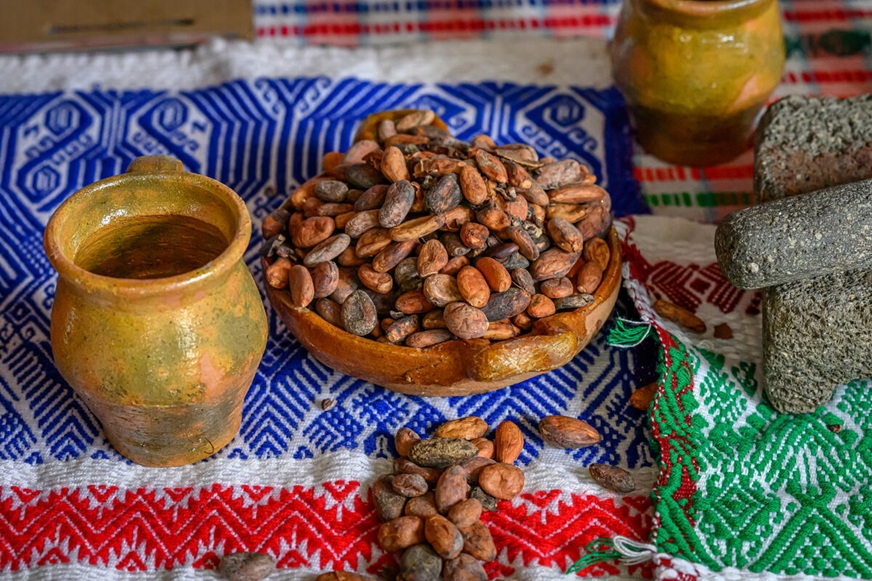 A bowl of cacao beans sits on a table with a jar and mortar and pestle. (Guatemala, 2024)