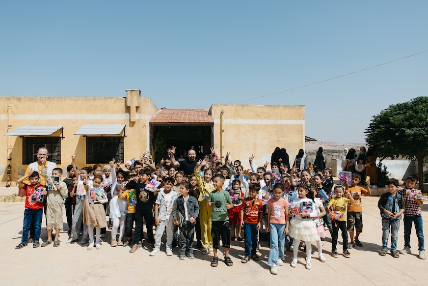 A large group of children pose for a photo outside a school in Syria.