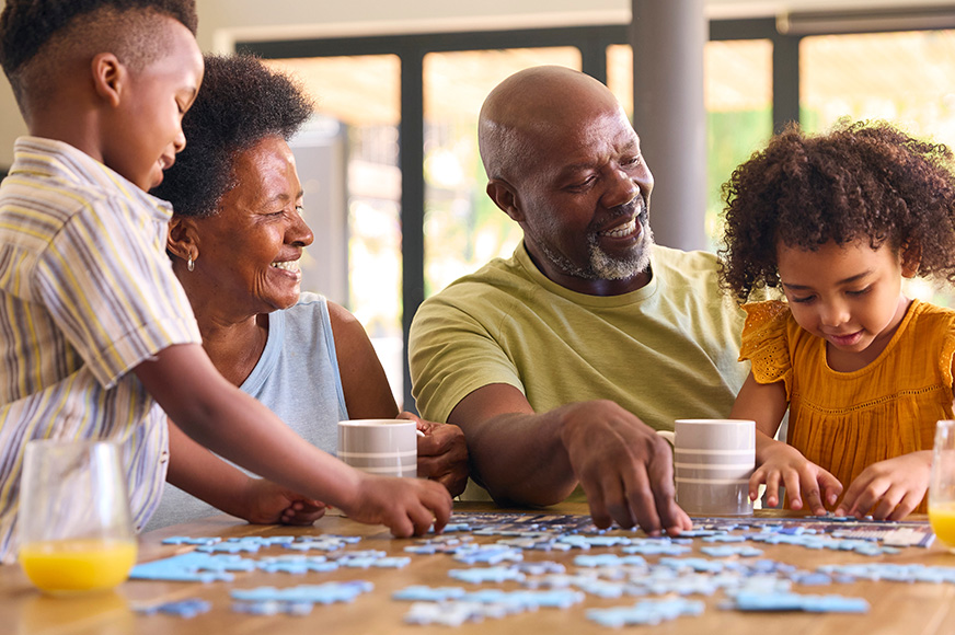 A family of four having fun doing a puzzle at their kitchen table.