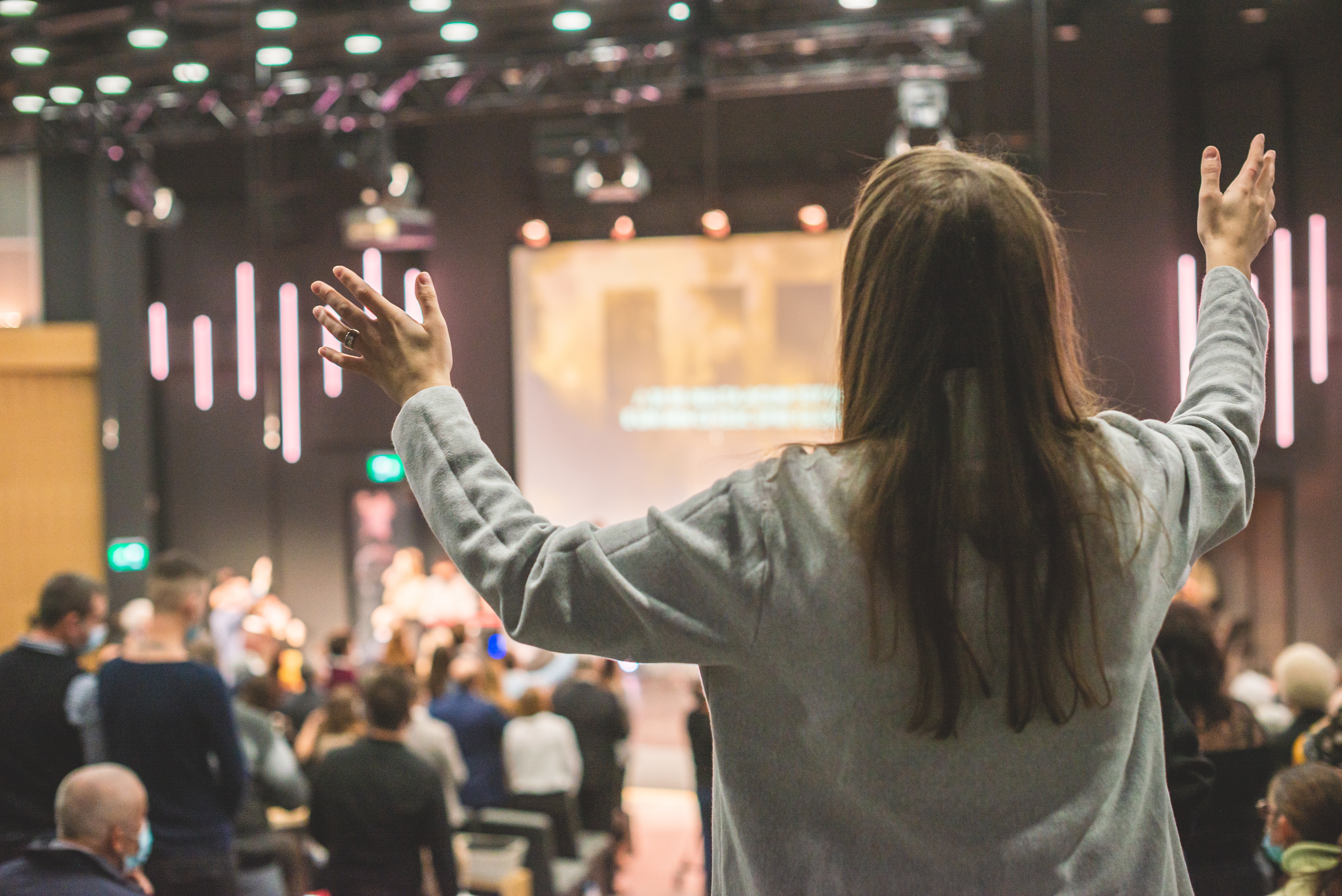 A women singing and raising her hands with fellow church congregants at an Easter Sunday church service.