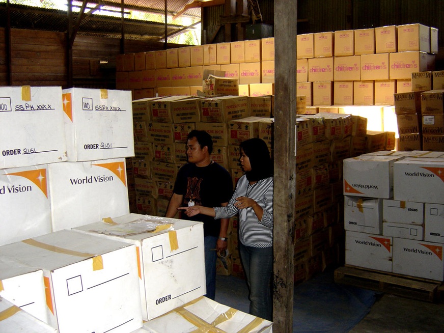 A man and a woman are in a warehouse, taking inventory of World Vision relief goods (Indonesia, 2005)
