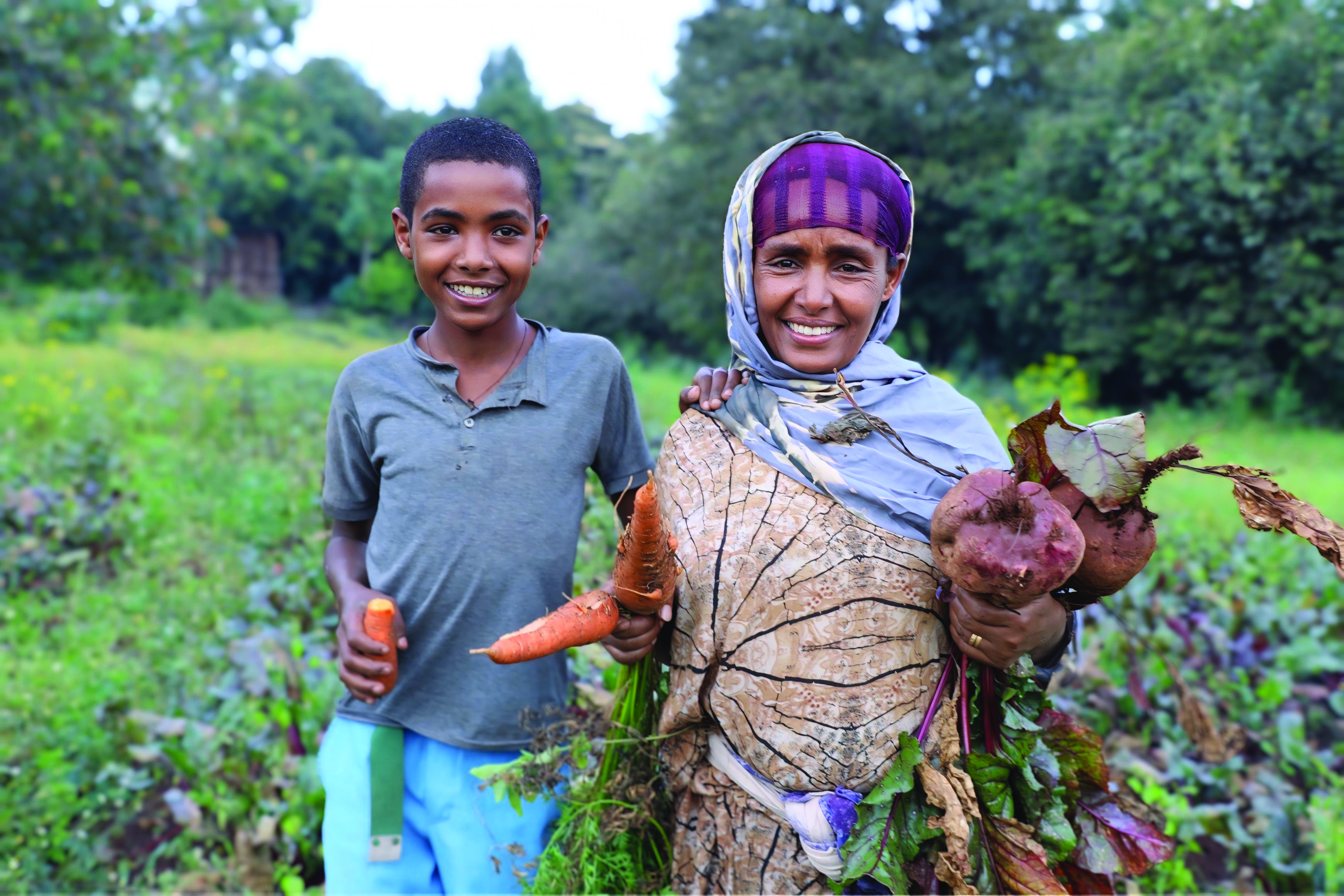 Mother and child showing produce pulled from the garden.