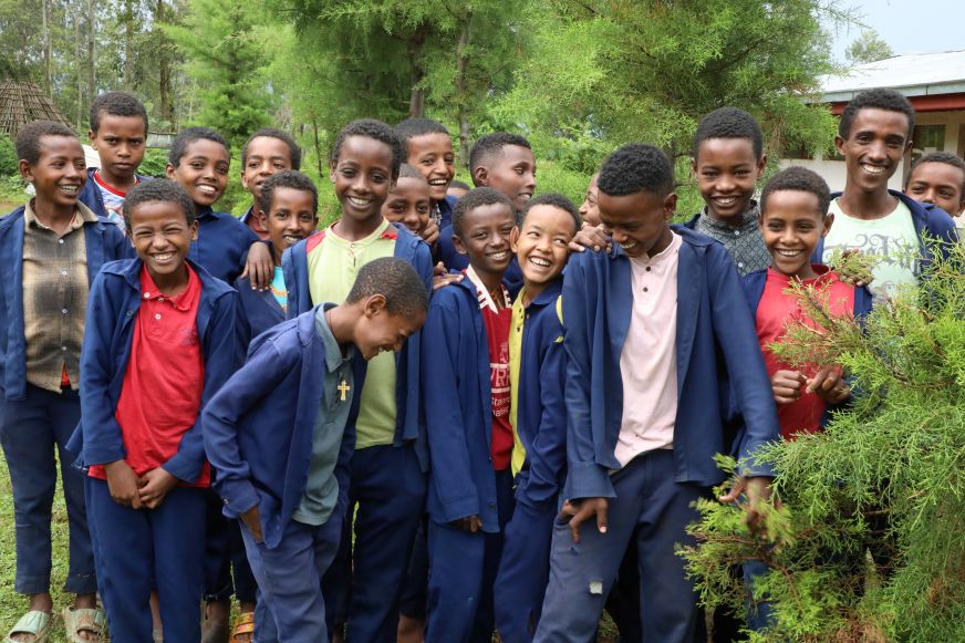 A group of adolescent boys in Gewata, Ethiopia, crowd together for a group photo.
