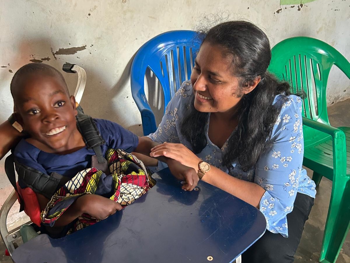 A woman and a child sit smiling at a table.