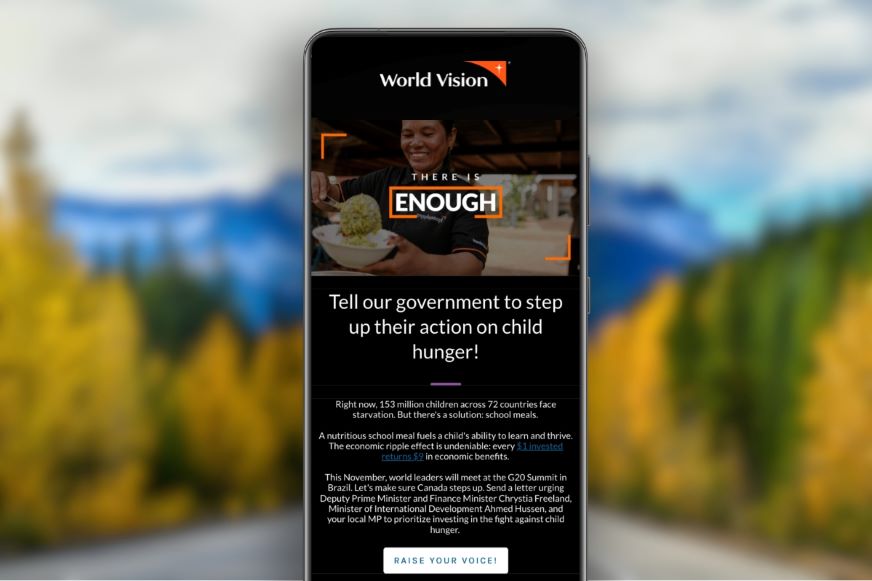 A World Vision advocacy email appears on a smartphone screen, with blurred mountains in the background.
