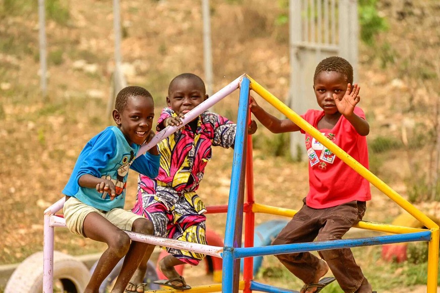 Three children playing in a playground. (Uganda, 2022)