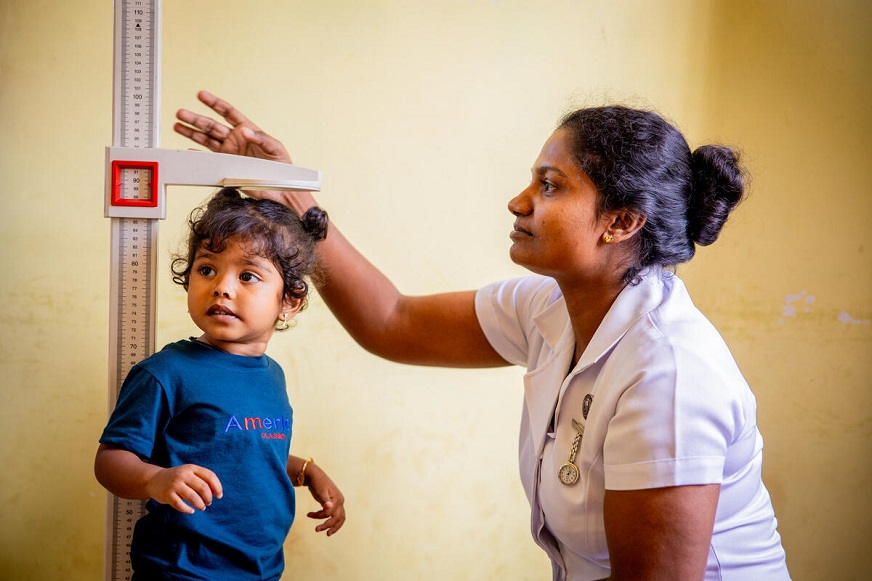 A young girl’s height is measured by a female healthcare worker. (Sri Lanka, 2025)