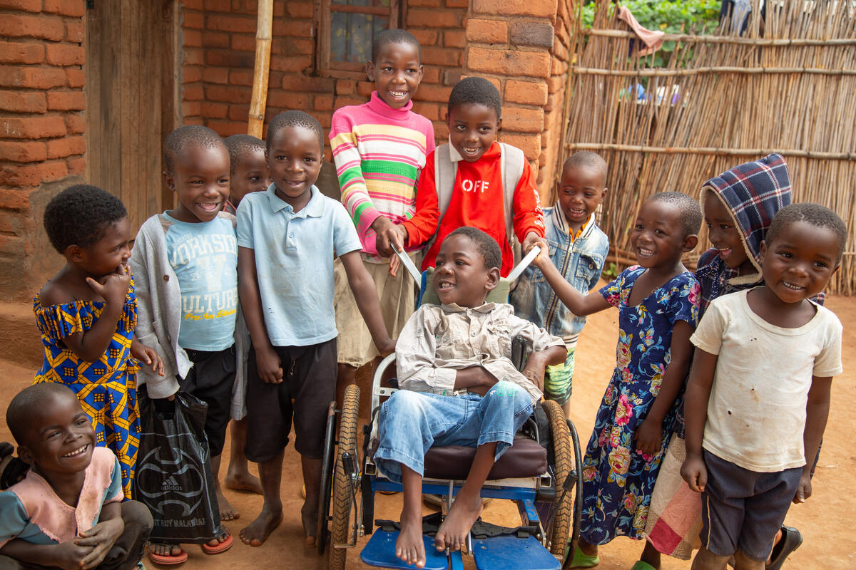 A group of children standing around a child in a wheelchair (Malawi, 2025)