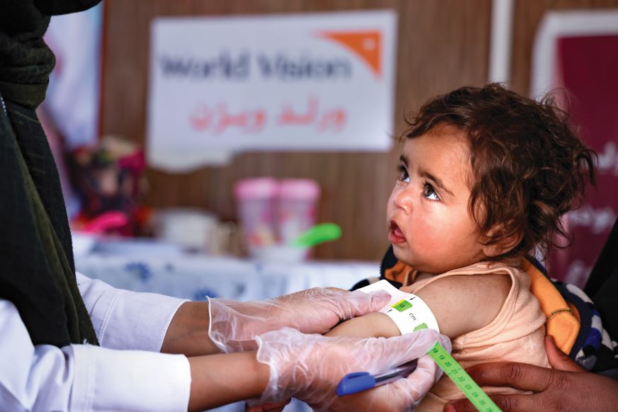 An infant has their upper arm circumference measured.