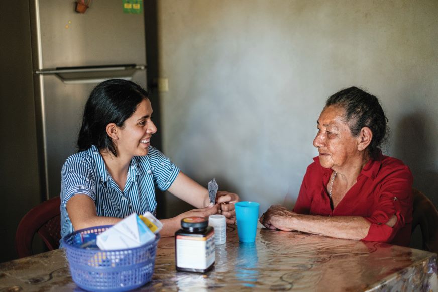 A young woman sits for a health consultation with an older woman.