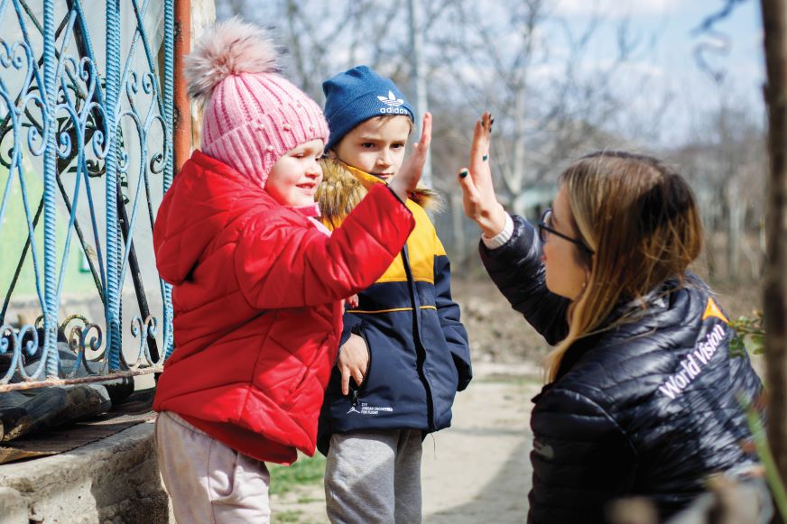 Two young children interact with a woman wearing a World Vision jacket in Moldova.