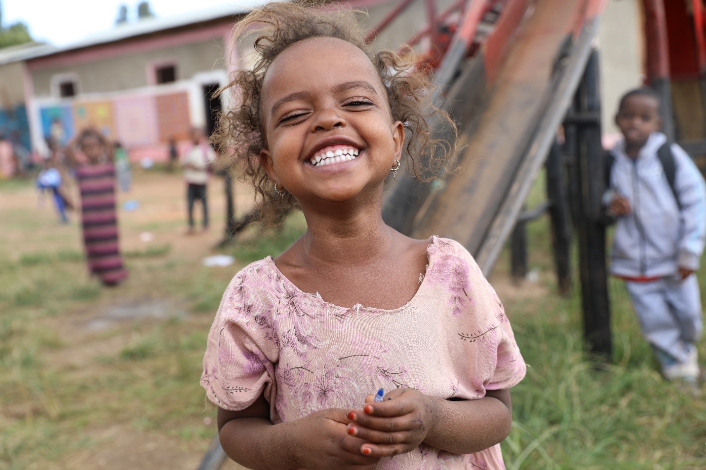 A girl smiles on the playground.