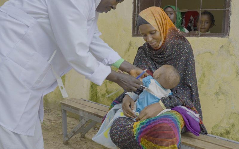 Horizontal blog image template - sudan-crisis-one-year-doctor-with-mother-clinic