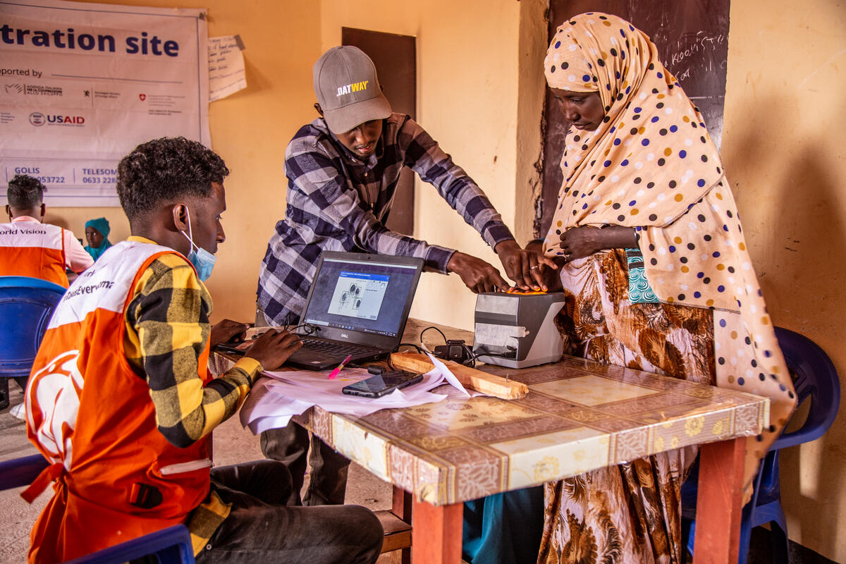 A mother in Somalia registers at a World Vision table to receive cash transfers.