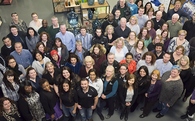 A large group is photographed from above, smiling toward the camera.