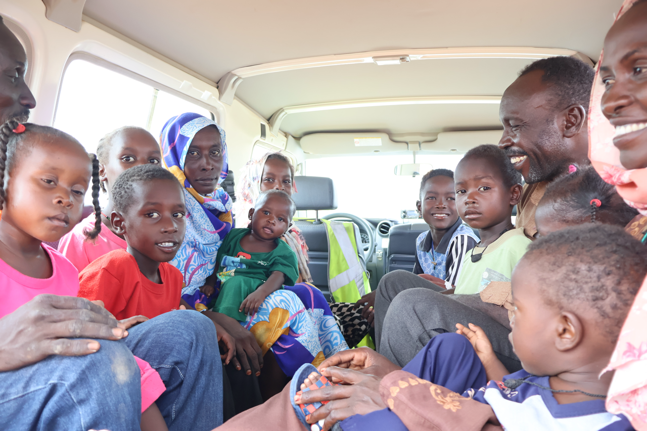 family_sits_back_of_van_smiling