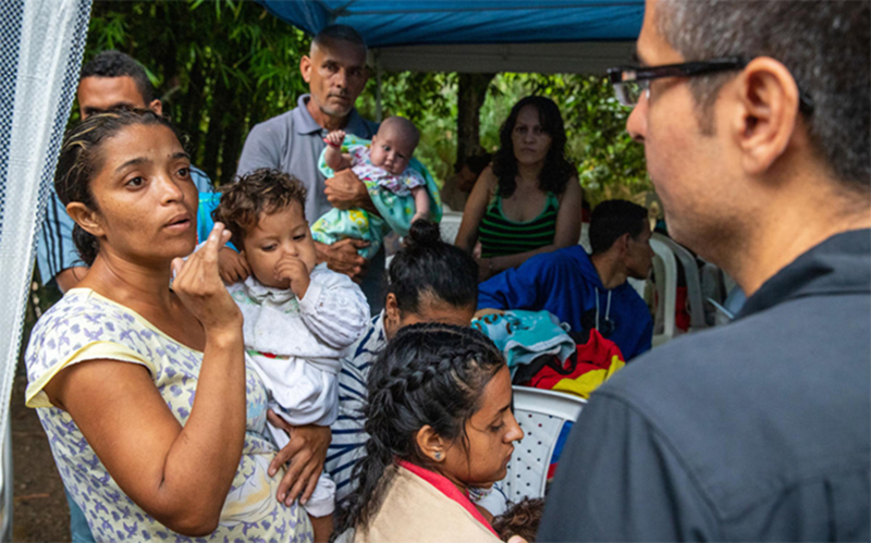 A Venezuelan mother carries her child while talking to a healthcare worker.