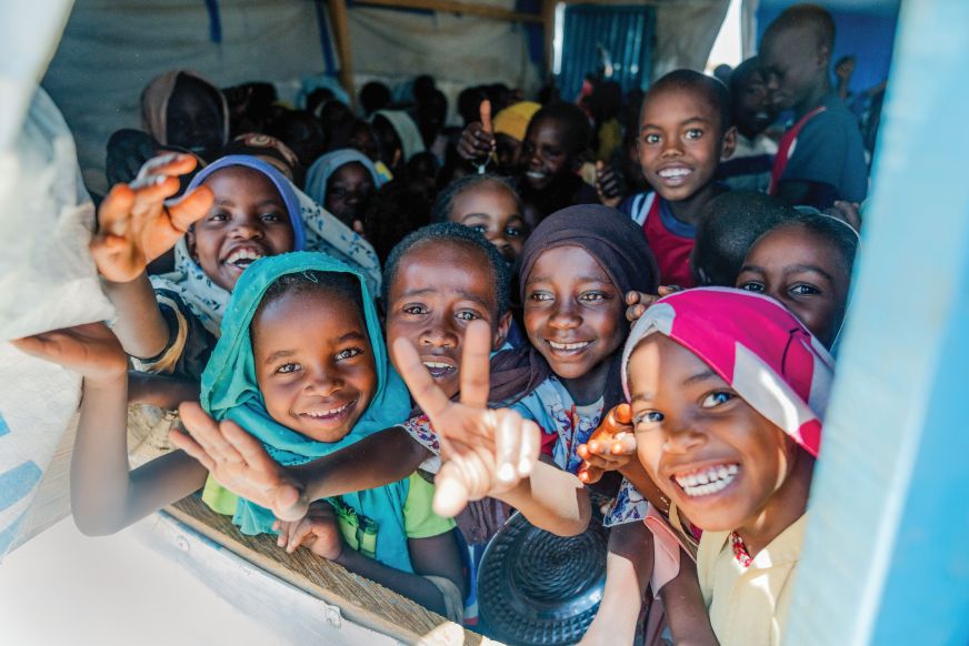 Sourires et signes de paix dans une tente communautaire