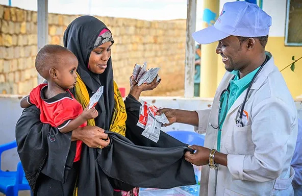 somalia-world-vision-staff-hands-mother-packs-of-ready-to-use-therapeutic-food.webp