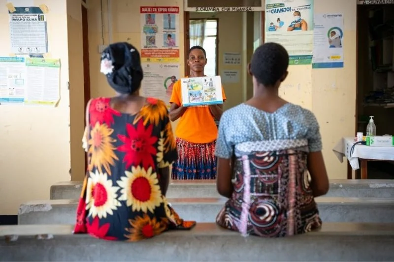 Two women learn together from a teacher.