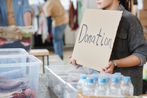 A volunteer holds a cardboard donation sign at a charity event. Photo: pexels.com