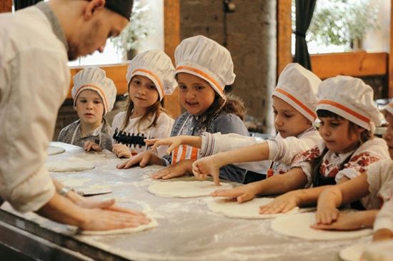 Kids baking class. Learning to make pizza with chef.