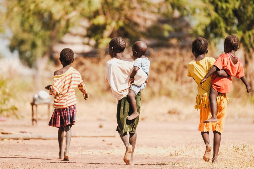 Trois enfants marchent sur un chemin de terre au Soudan du Sud. Deux d’entre eux portent des tout-petits sur la hanche.