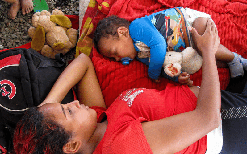 Une mère et son enfant se reposent sur des couvertures étalées par terre.