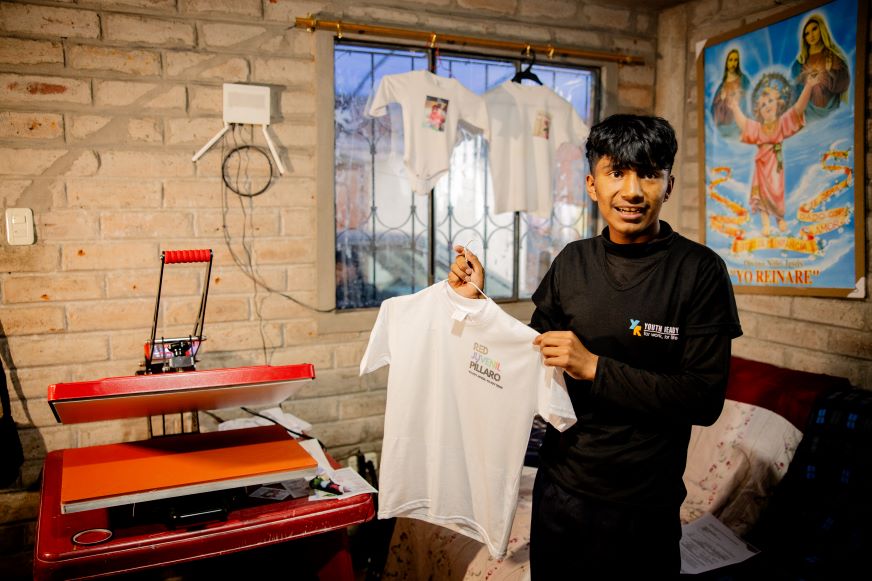 Un adolescent tient un chandail près d’une machine d’impression à Pillaro, en Équateur.