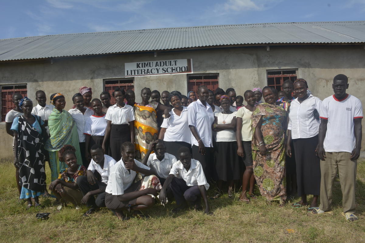 Un groupe d'adultes pose pour une photo devant l'école d'alphabétisation pour adultes « Kimmy », au Soudan du Sud.