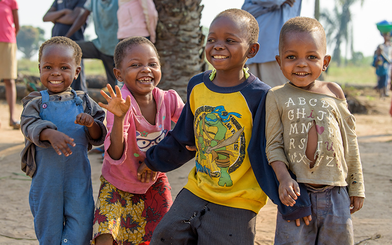 Quatre jeunes enfants originaires de la République démocratique du Congo sourient et font signe à la caméra d’un air enjoué.