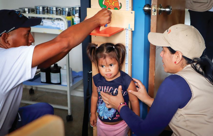 Une petite fille se fait mesurer par des employés de World Vision.