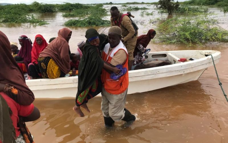 Un homme soulève une femme d'un petit bateau flottant sur les eaux de crue pour l'emmener en terrain surélevé.
