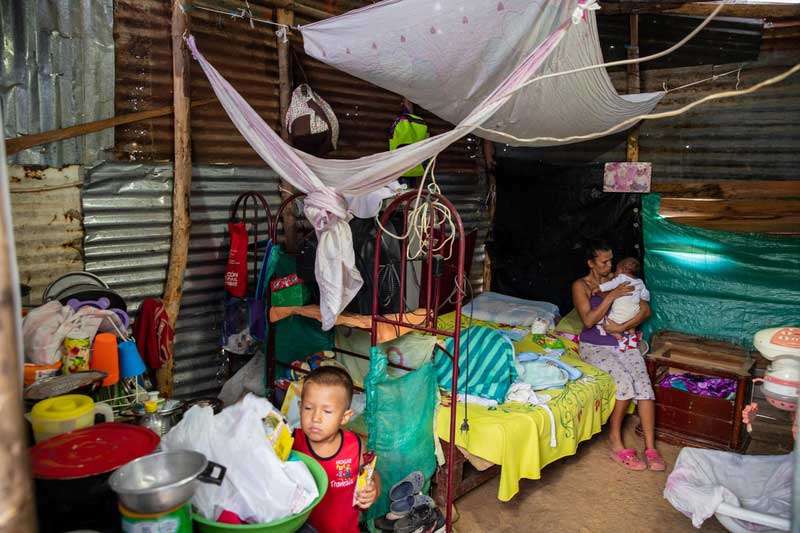 Une migrante vénézuélienne dans sa tente avec ses deux enfants.