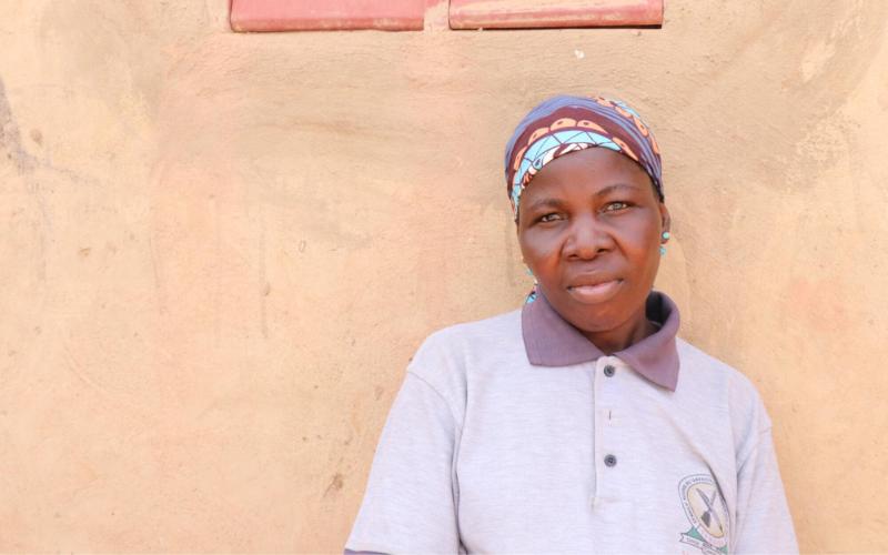 Une femme qui a fui son domicile en raison de violences au Burkina Faso se tient debout, le visage grave.