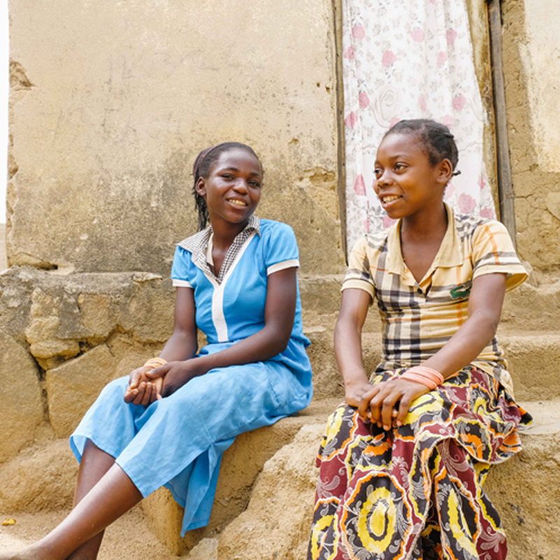 Deux filles en République centrafricaine sont assises devant un immeuble.