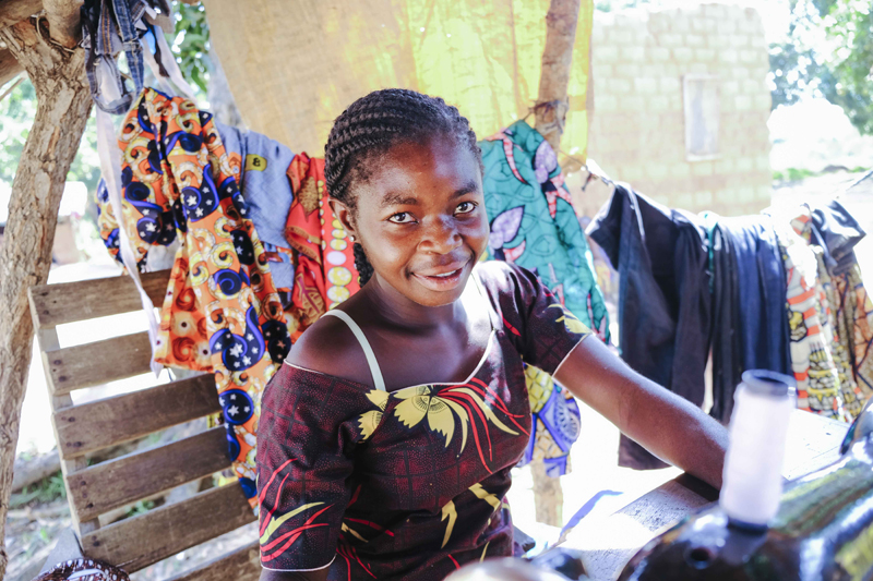 Une femme centrafricaine est assise devant une machine à coudre.