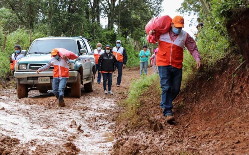 Au Honduras, un VUS et des travailleurs vêtus de vestes World Vision transportent des fournitures d'urgence sur une route boueuse.