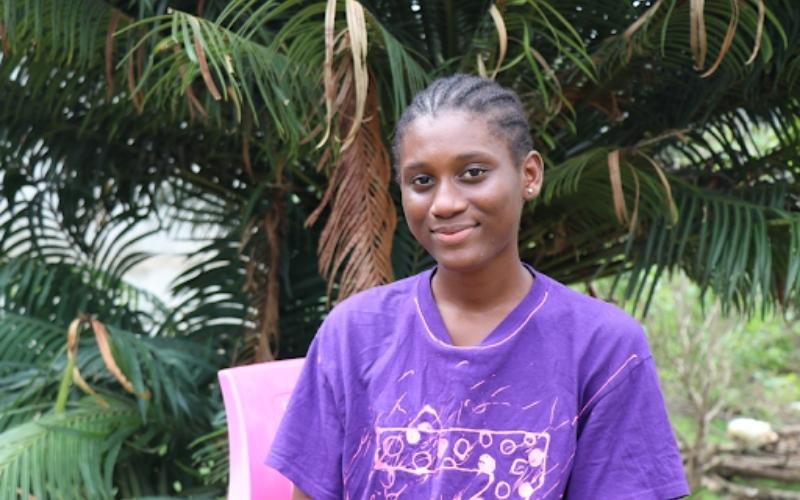 En Sierra Leone, Tenema se tient devant des palmiers.