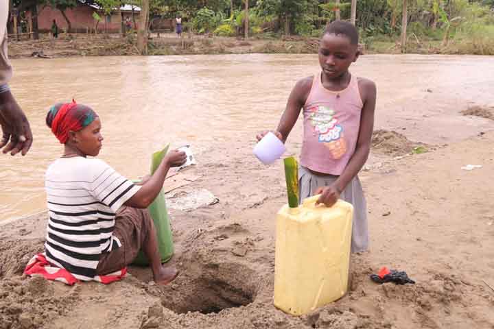 Deux femmes qui ramassent de l'eau sale.