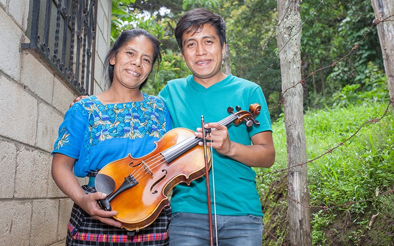 Tomasa et Gustavo tiennent ensemble son alto devant leur maison au Guatemala.