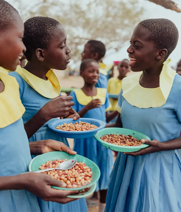Les élèves tiennent des bols de nourriture et discutent entre eux dans le cadre d'un programme de repas scolaires.