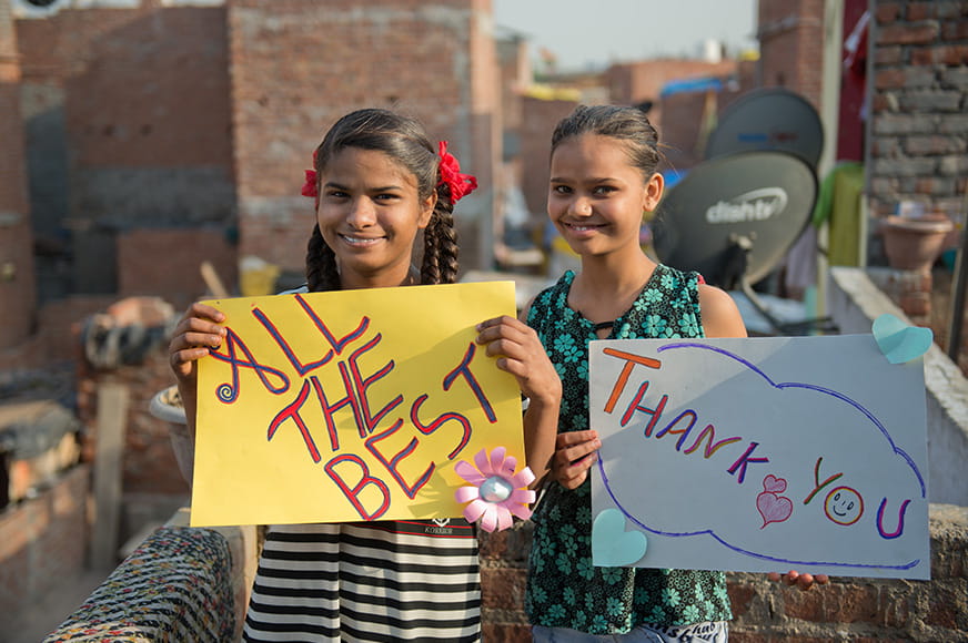 Roshni and her friend holding posters with messages of gratitude and well wishes for Meghan Markle.