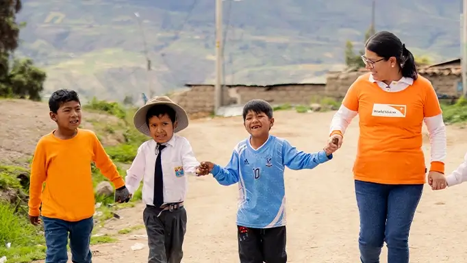 A group of children walk with a World Vision staff.