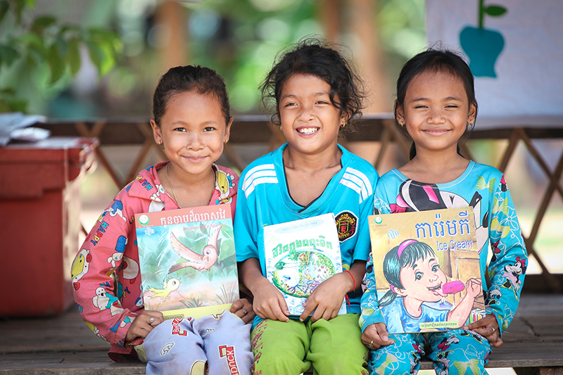 Three girls smiling with book